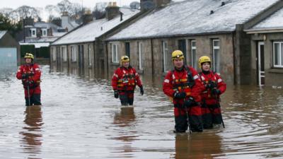 Rescue workers walking in flooded street