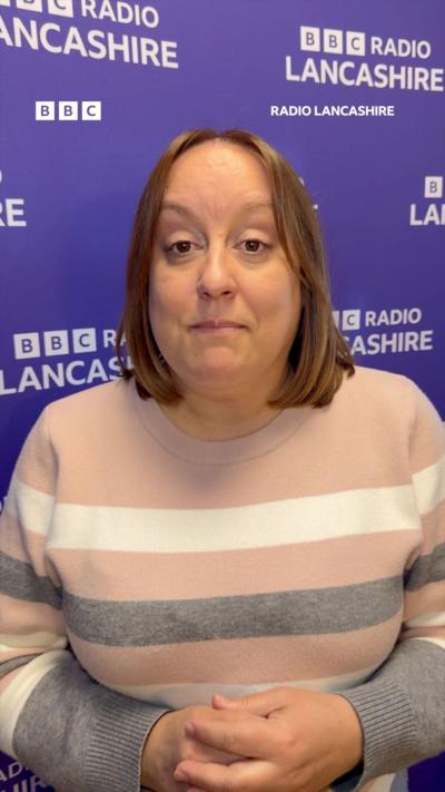 Dark haired woman in front of a purple and white BBC Radio Lancashire backdrop 
