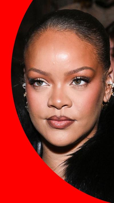 Woman with black hair tied back, ear piercings, and a black fur collar on her clothing.