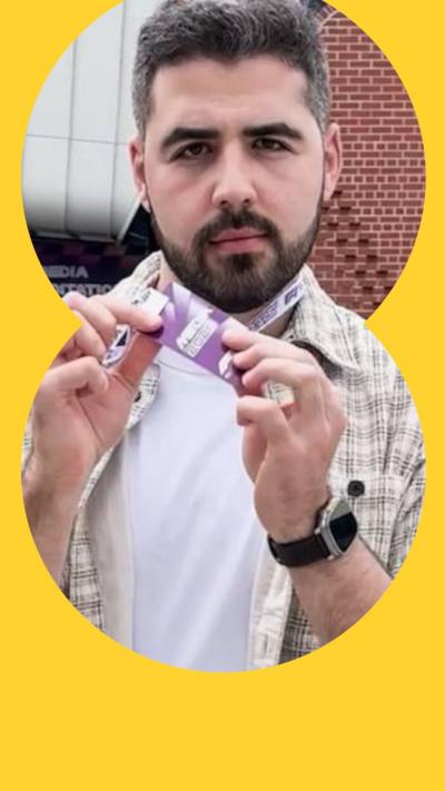 A bearded man in a checked shirt holds a purple pass