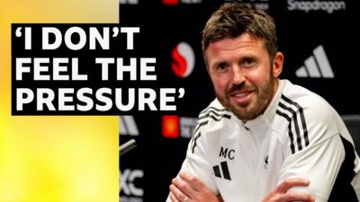 Interim Manchester United head coach Michael Carrick smiling. He is wearing a white Man United jumper.