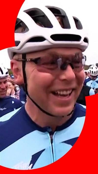 Sir Chris Hoy dressed in cycling gear, smiling and surrounded by other cyclists