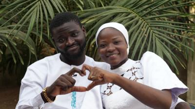 Olanrewaju and Kaosara next to each other using their hands to form a shape of a heart