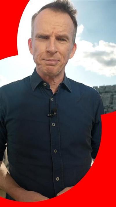 A man, John Sudworth, has short hair and is wearing a blue shirt with the sleeves rolled up.