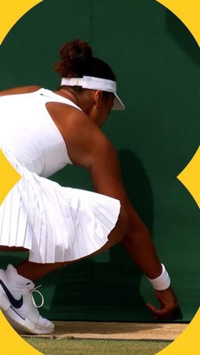 Naomi Osaka bends down on a tennis court - she is dressed in white