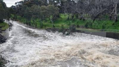 A torrent of water runs down a country road in Australia after the south of the country was hit by severe storms.