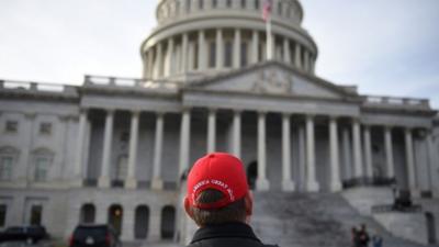 A supporter wears a "Make America Great Again" cap look on outside the US Capitol one day ahead of the inauguration of US President-election Donald Trump, in Washington, DC