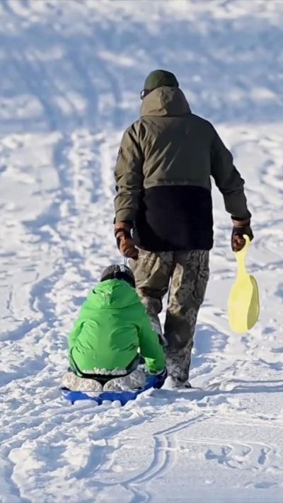 A child on a sled, being moved by an adult