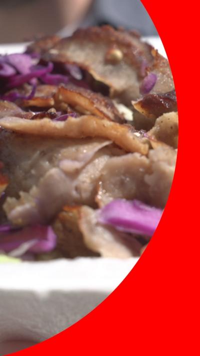 A close up strips of kebab meat in a white carton with purple cabbage.