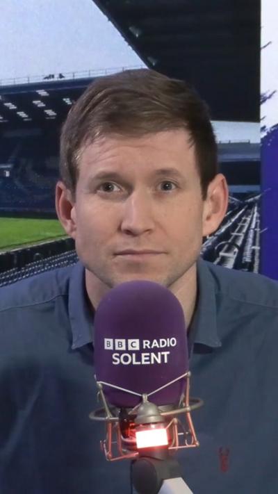 A man speaks into a BBC branded microphone.