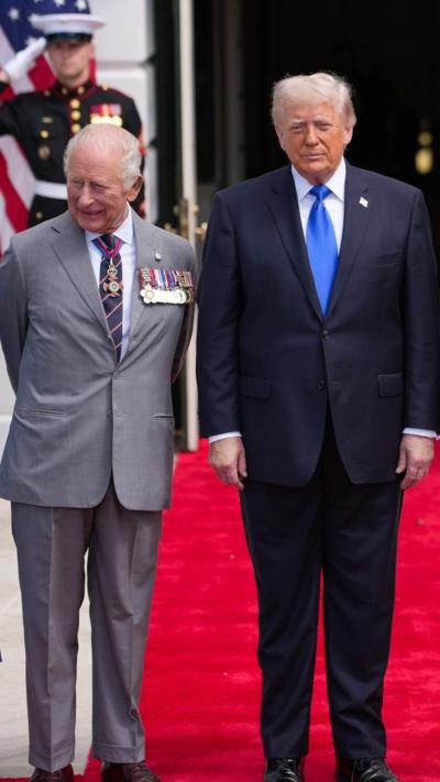 The King stands next to Donald Trump on a red carpet outside the White House.