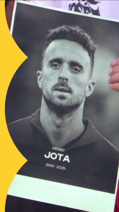 A fan holding a black and white photo of Diogo Jota during a moment of silence
