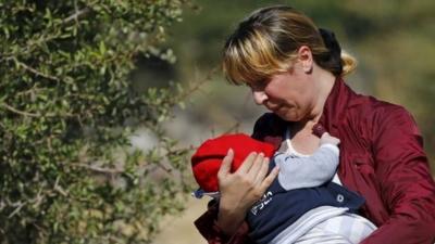 A Syrian migrant woman, holding a baby, on the Greek island of Lesbos