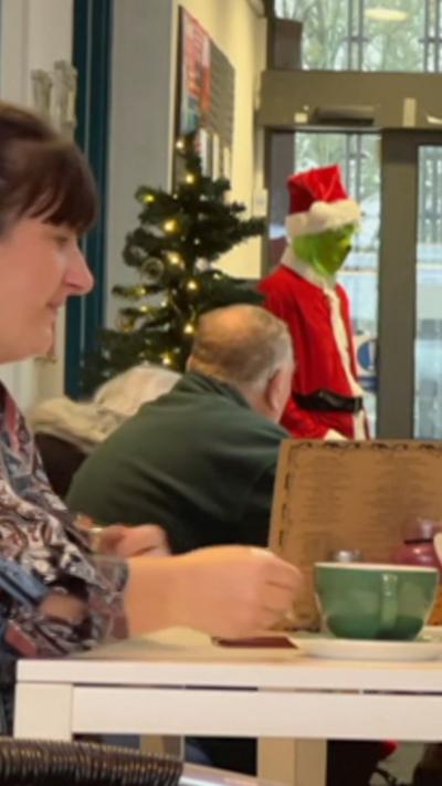A woman sat at a table drinking out of a green mug