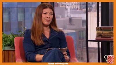 Laura Pomfret in the Morning Live studio, sat down, wearing a blue denim jumpsuit.