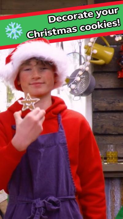 A young teen holds up a decorated star shaped biscuit.