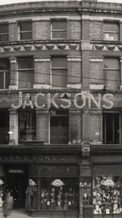 A black and white photo of the front of a department store with the word Jacksons.