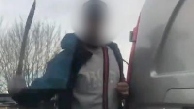 A man attacking a car with a machete