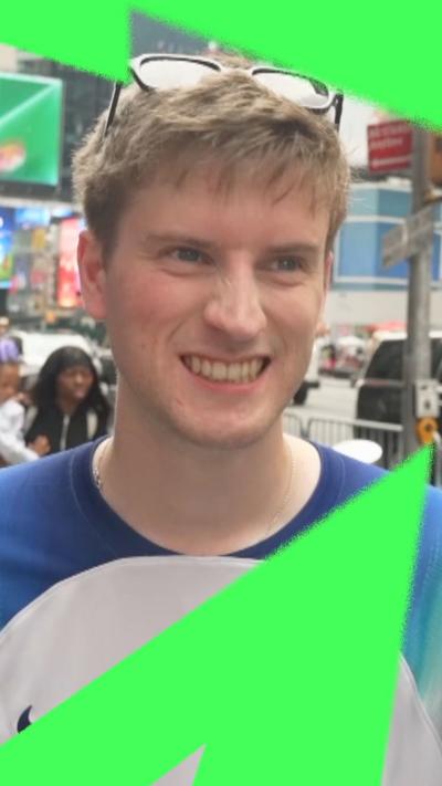 A young man wearing an England jersey crinkles his nose.