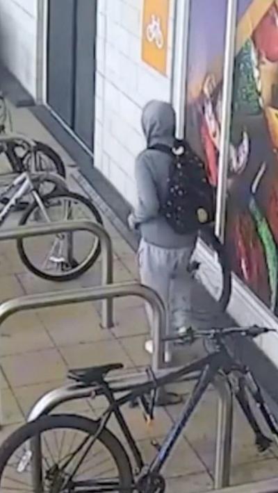 Man wearing grey sweatpants and grey hoody with the hood up. He has a black rucksack on his back.