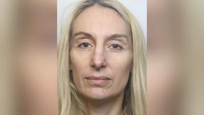 A custody mugshot of a woman with long blonde hair