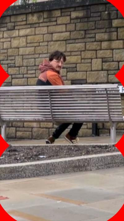 A man sits on a bench facing a wall 