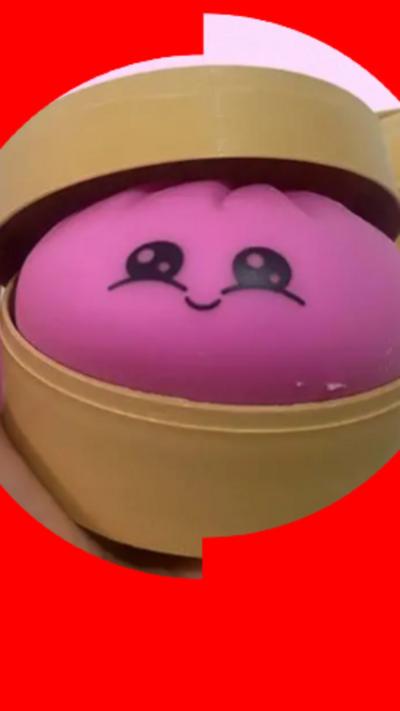 A pink dumpling squishy inside a yellow circular container.