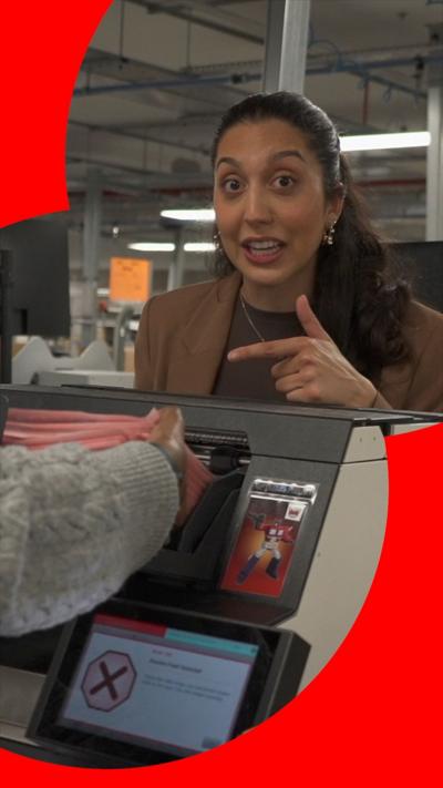 A woman with dark hair pulled away from her face points at exams being loaded into a machine
