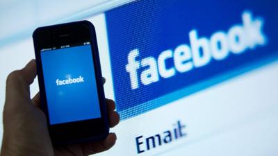 A Apple iPhone displaying the Facebook app's splash screen in front of the login page in Washington, DC.