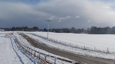 Snow showers looming over a bright, snow-covered field.