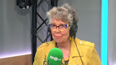 Prue Leith in yellow jacket sat in BBC radio studio