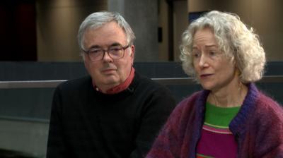 John Newman and Rose Marie Burke - he is wearing a dark jumper and has glasses and white hair, she has a purple and green top with shoulder length white hair.