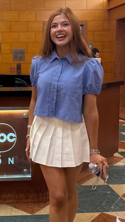 Sophie Lennon wearing a blue shirt and white skirt smiling at the camera 