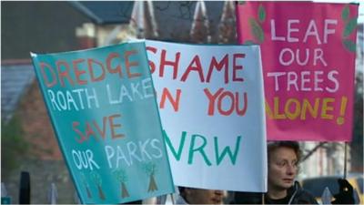 Residents hold signs objecting to the removal of the trees