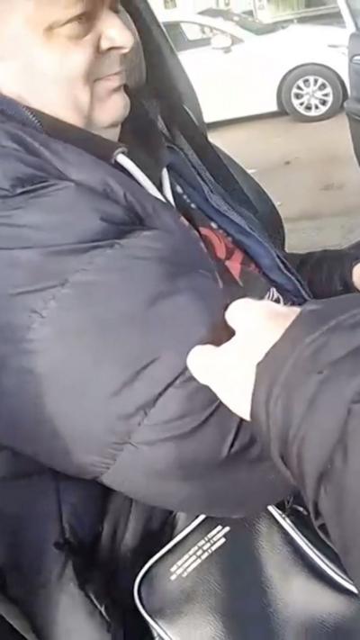 A man behind the wheel of a car being grabbed by a police officer 