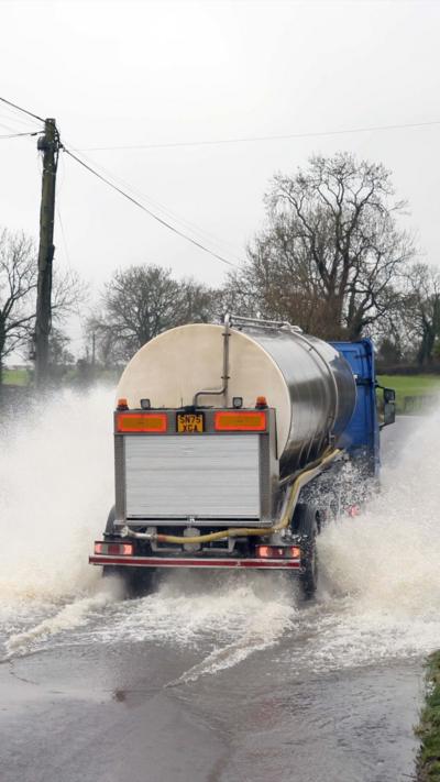 A truck driving through a flooded road. 