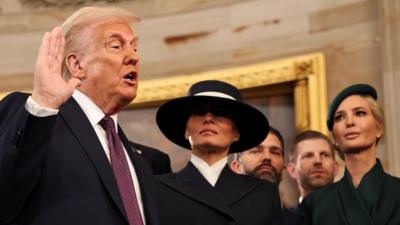 Donald Trump raises his hand to take an oath, Melania, Ivanka and Donald Trump Jr are standing beside him