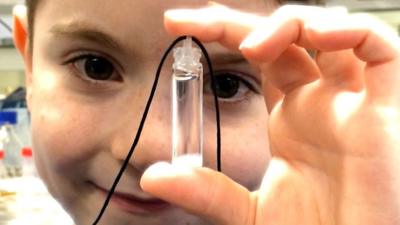 Alfie Oswick holding a DNA necklace