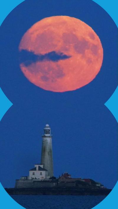 A pink moon over a lighthouse