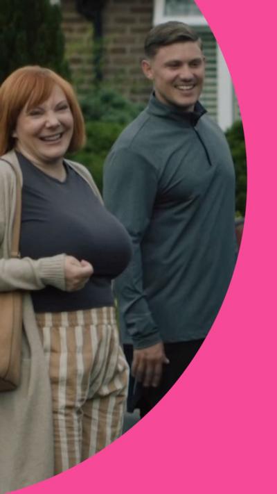 A woman and a man stand in a driveway, smiling