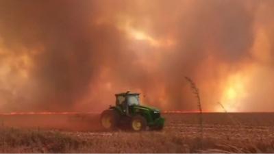 A tractor in front of smoke and flames