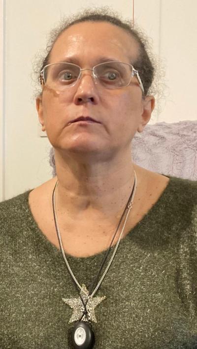 A woman wearing glasses with a green top and a gold star on it. She's wearing a pendant