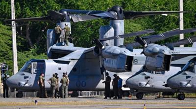 A group of US Marine Corps working with a MV-22 Osprey aircraft.