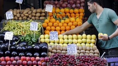 A vendor displays fruits in his shop in a local market in central Athens