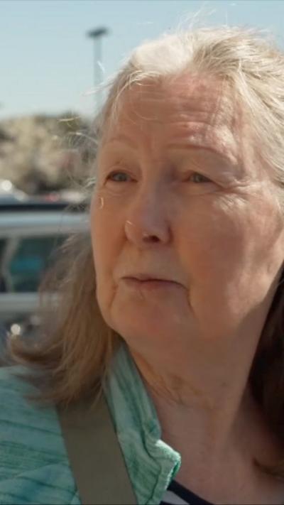 A woman in a green top speaks with a BBC reporter on a busy street