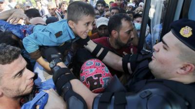 A policeman helps a boy as people board a bus in Croatia