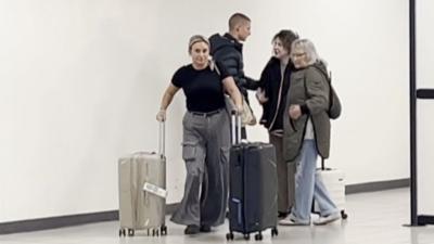 Bella Culley arrives at Luton Airport as her mum pushes two suitcases