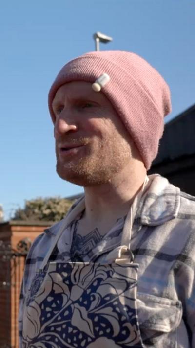 A man in a pink hoodie and a blue and white patterned apron