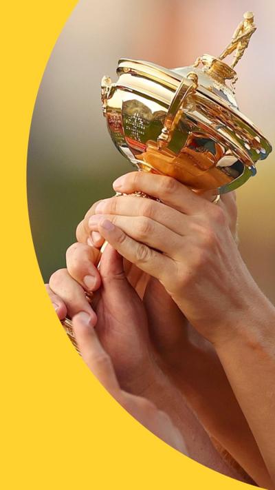 A close-up of the Ryder Cup trophy with several hands on it or pointing to it