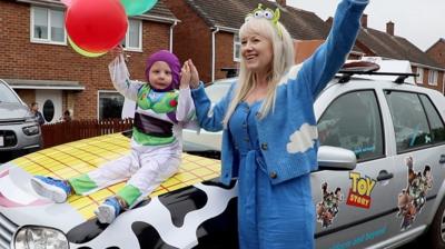 Irene Reid and Noah posing with the Toy Story car